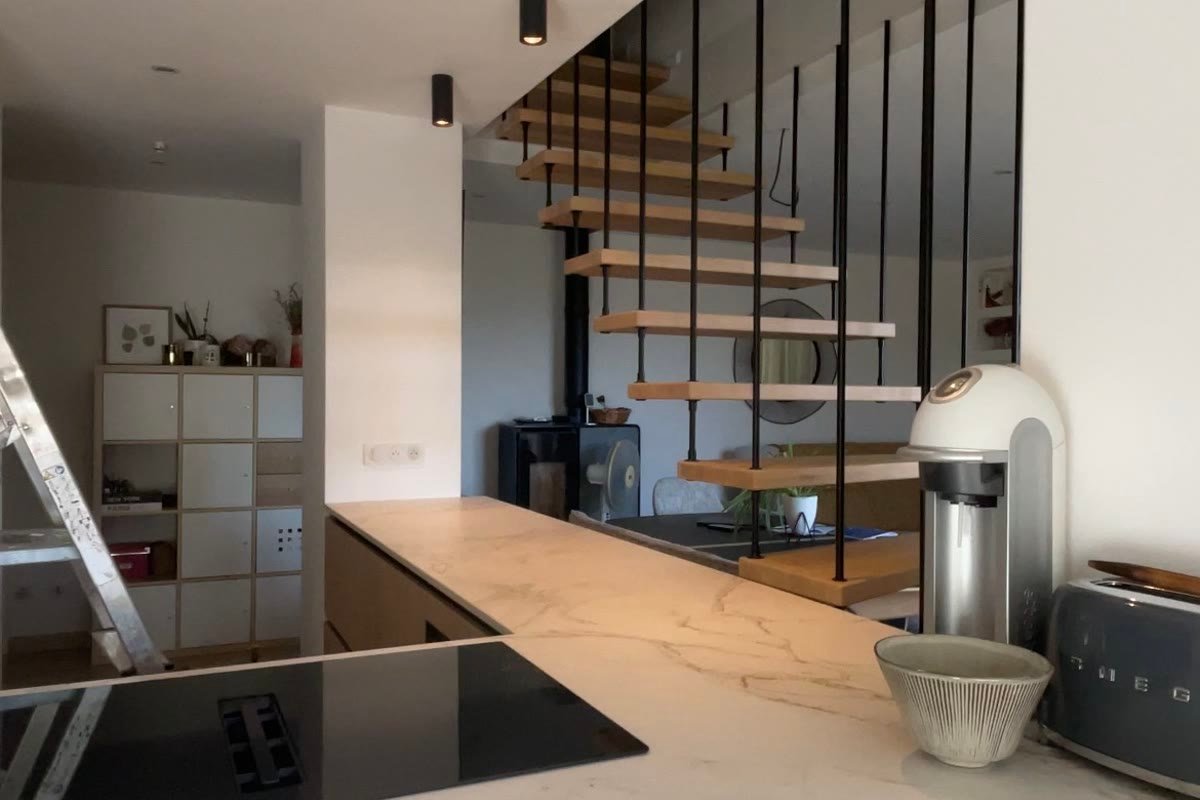 Cuisine équipée de spots encastrés et de suspensions noires au-dessus du plan